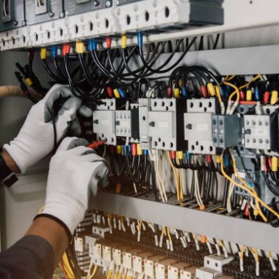 Electrician engineer tests electrical installations and wires on relay protection system.